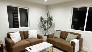 A living room with two brown sofas, a white marble coffee table, and a small potted plant.