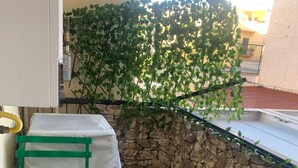 A small outdoor seating area with a green table and chairs, a potted plant, and a stone wall. - Girasole Marino - Beautiful apartment near the sea and the center of Palermo (Palermo)