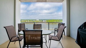 Un balcone con tavolo e sedie, un barbecue e vista su un fiume e edifici in lontananza.