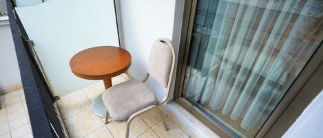 A small room with a chair and a table, a sliding glass door, and a tiled floor.