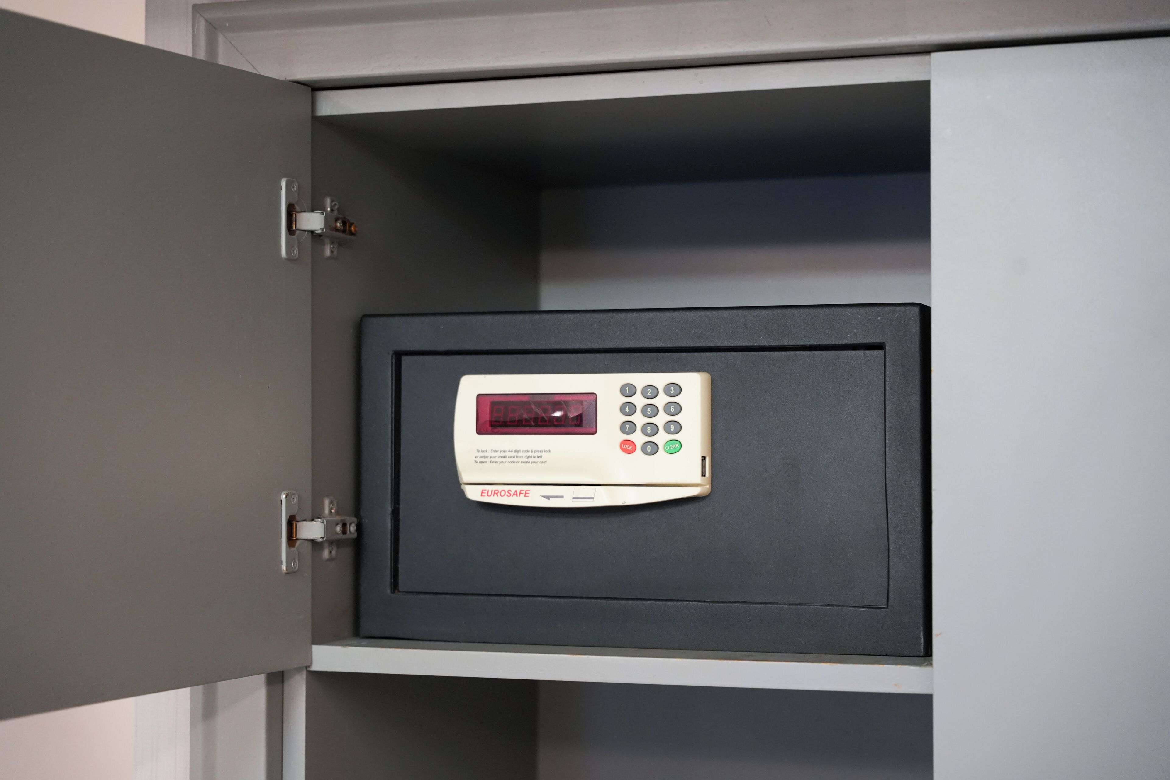 A safe with a digital keypad and a display, placed inside a cabinet.