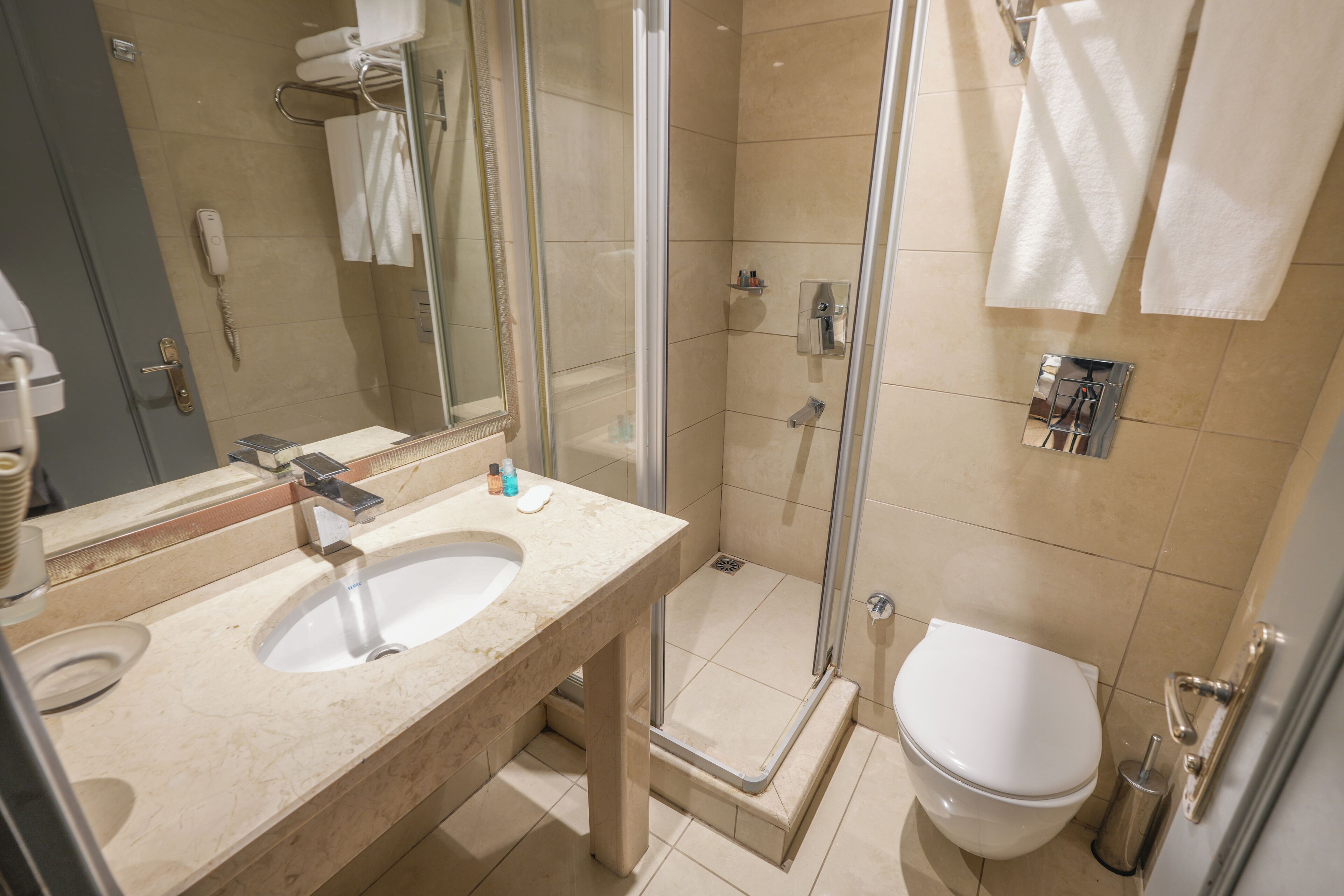 A bathroom with a sink, mirror, shower, and toilet.