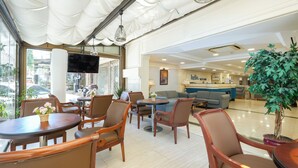 A hotel lobby with a reception desk, seating area with chairs and tables, a large potted plant, and a television mounted on the wall. - Taksim Stare Hotel (Istanbul)
