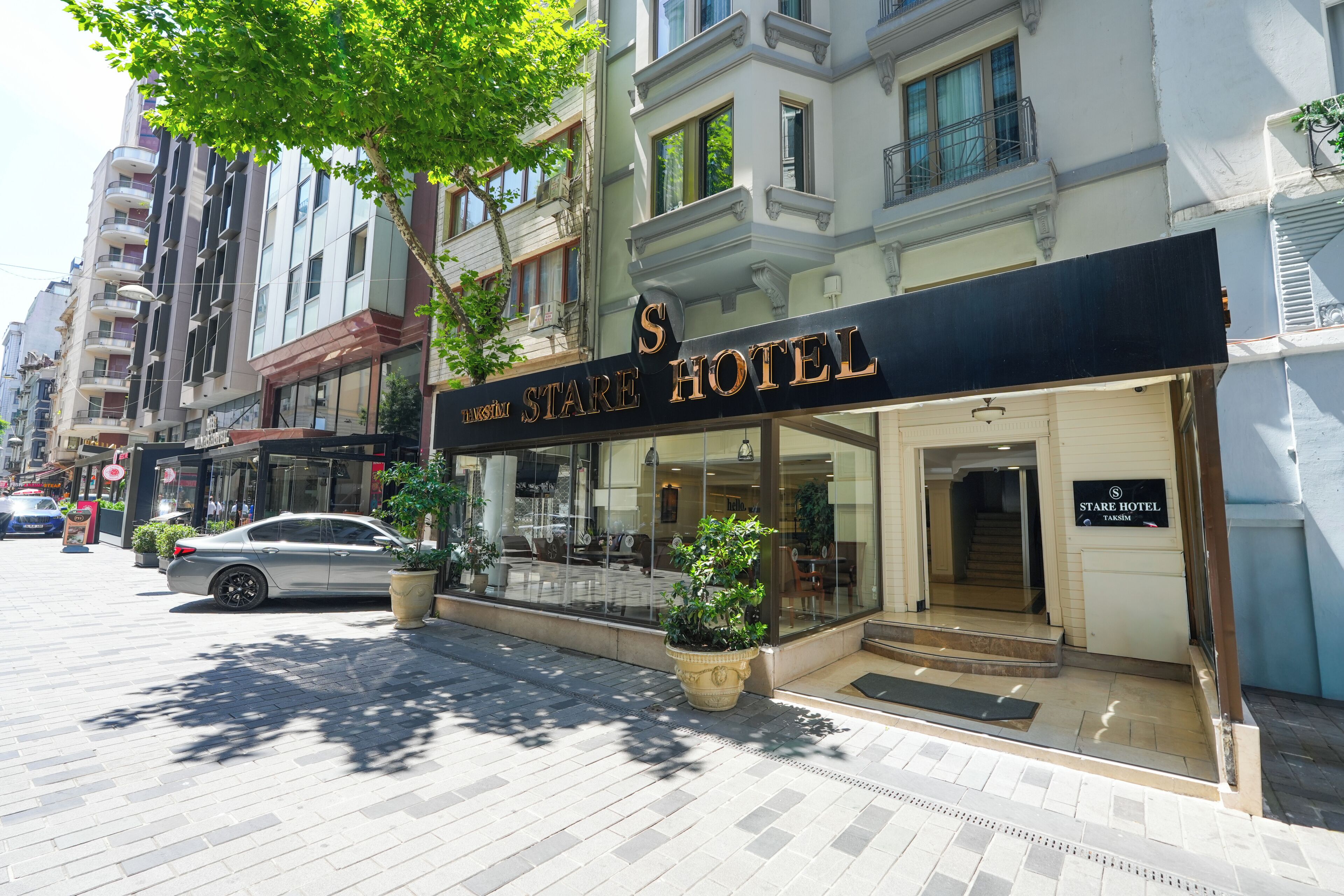 A hotel with a prominent sign, a glass facade, and a staircase leading to the entrance.