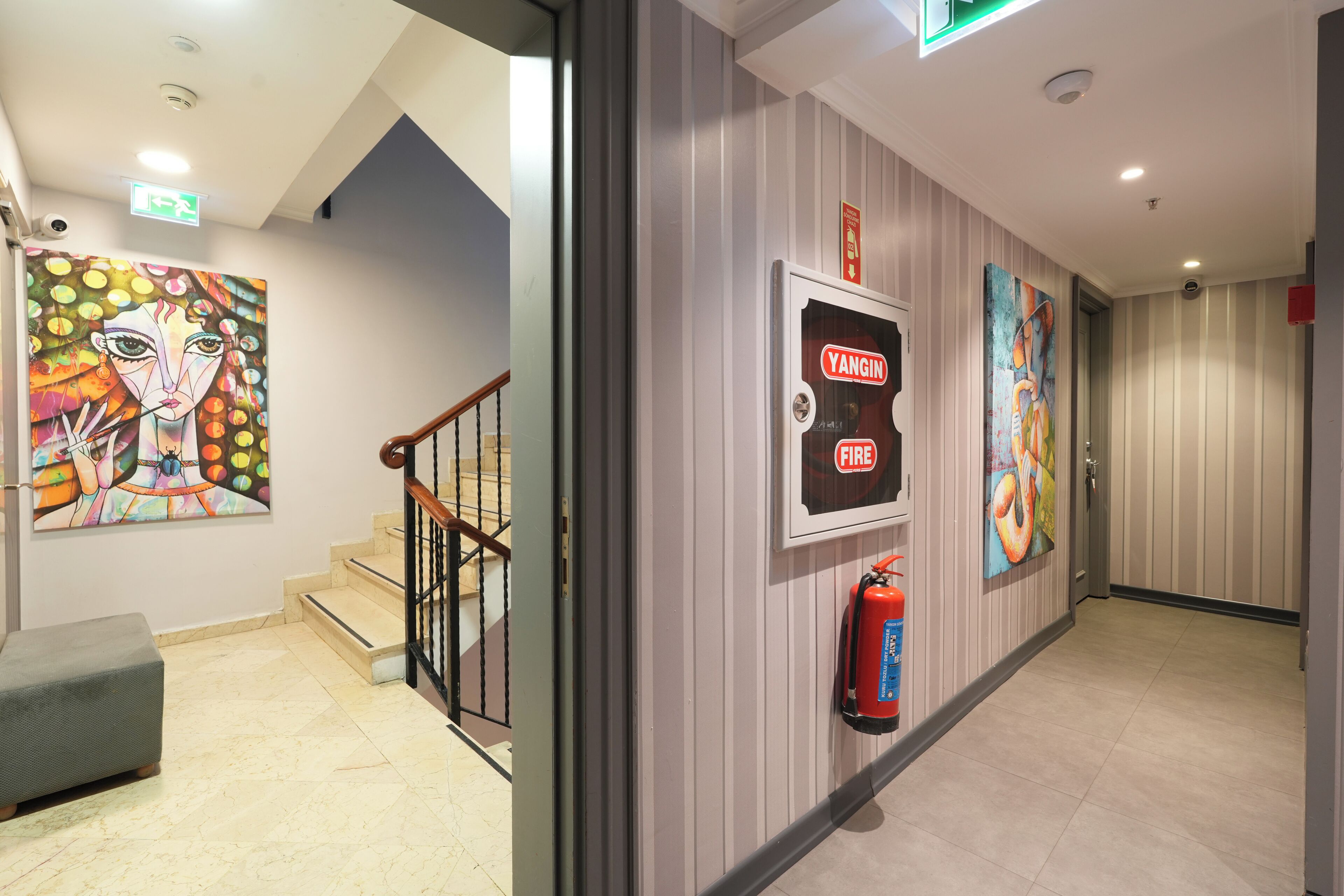 A hallway with a fire extinguisher mounted on the wall, a staircase, and a bench.