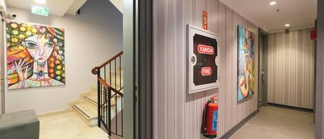 A hallway with a fire extinguisher mounted on the wall, a staircase, and a bench.