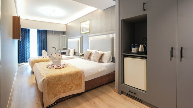 A hotel room with a large bed, a wardrobe, a small kitchenette, and a bathroom with a mirror. - Taksim Stare Hotel (Istanbul)