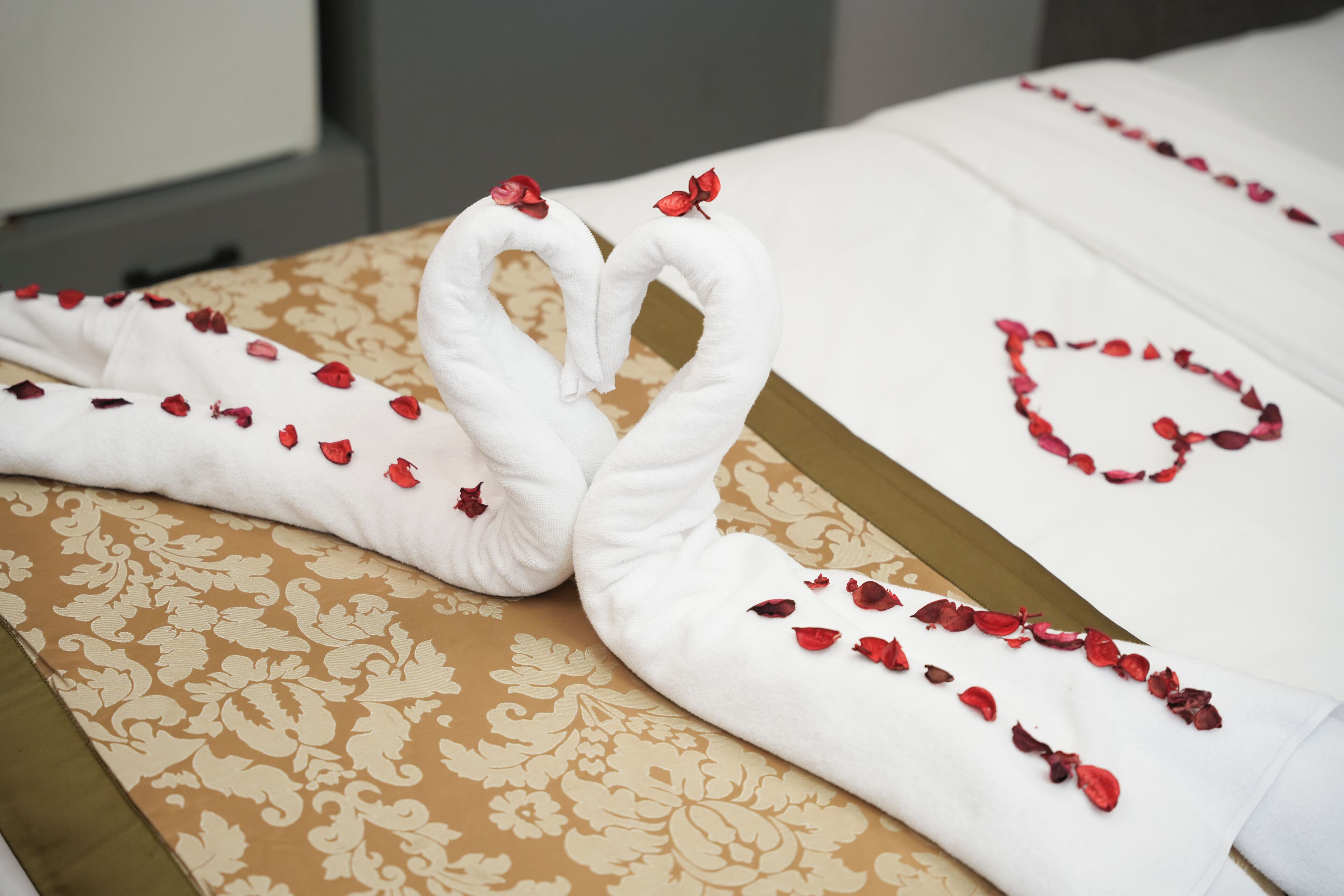 A bed with a floral patterned bedspread and a white pillow with a heart-shaped design.