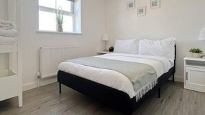 Um quarto com uma cama, mesas de cabeceira, uma janela e um radiador.