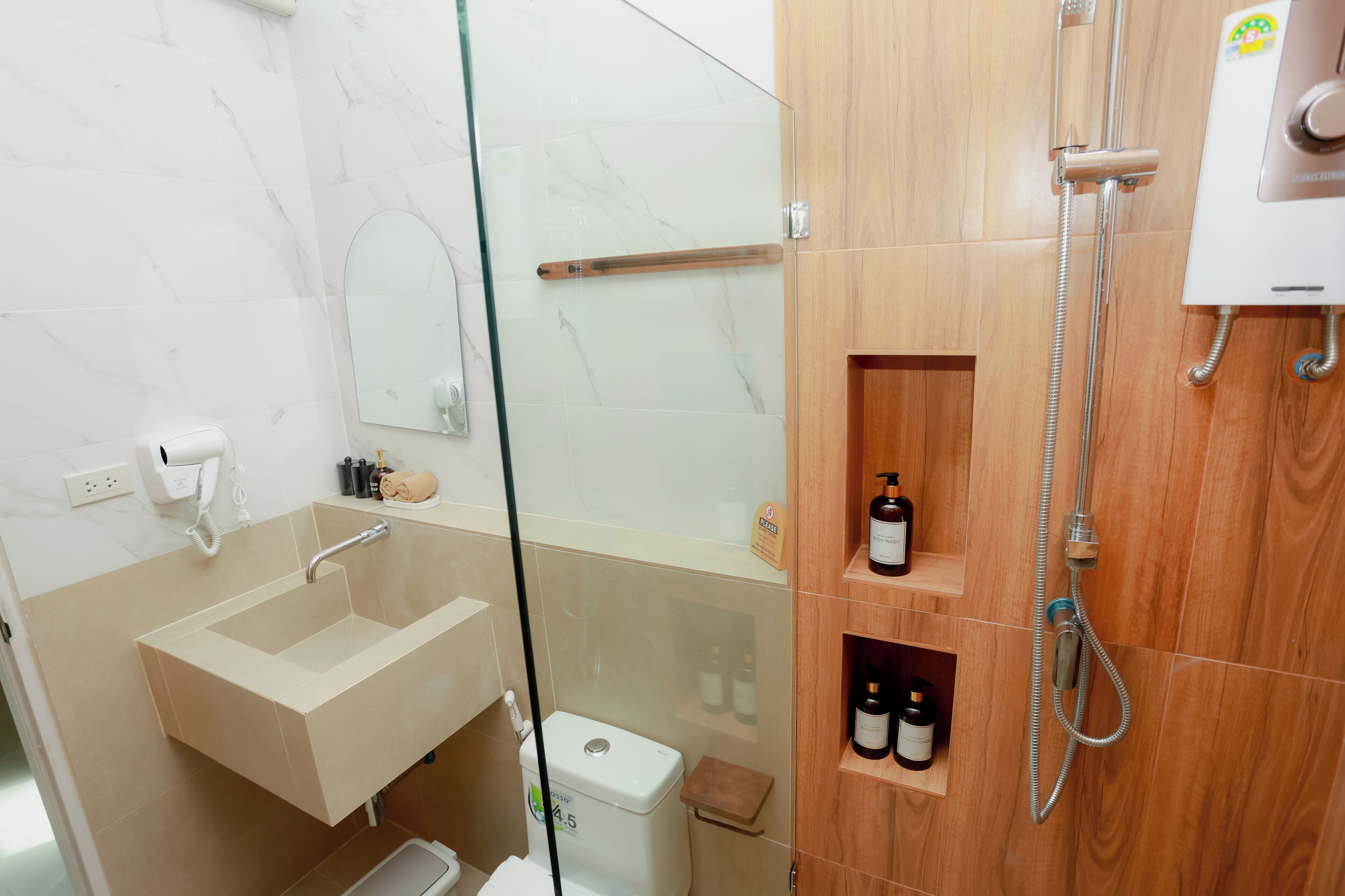 A bathroom with a glass shower enclosure, a sink, and wooden shelves with toiletries.