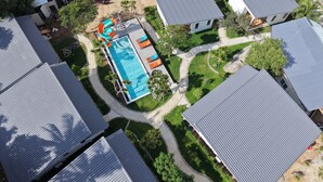 Vista aérea de una zona residencial con varias casas, una piscina y un tobogán pequeño.