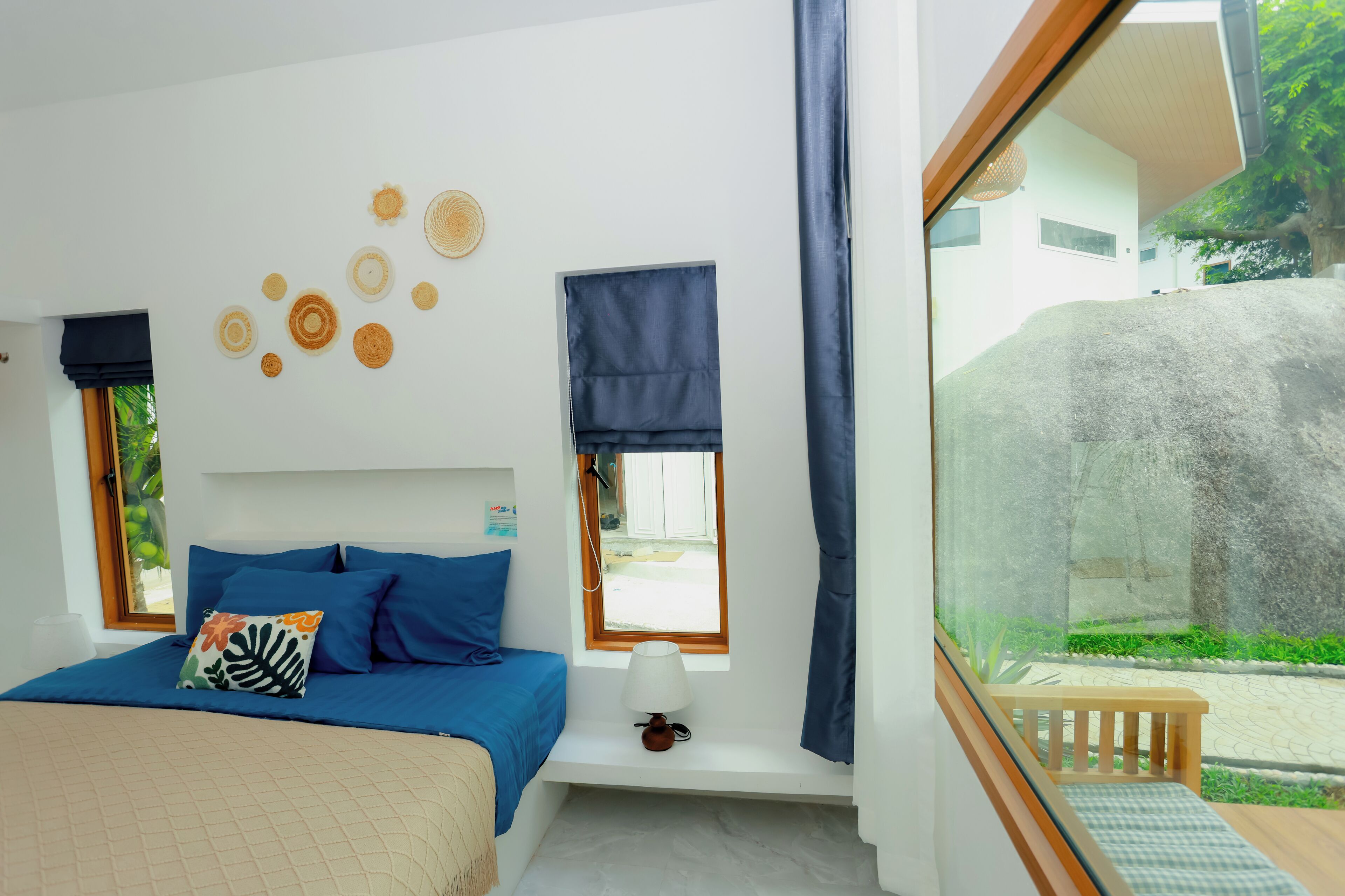 Een slaapkamer met een bed, een raam, een nachtkastje en uitzicht op buiten.