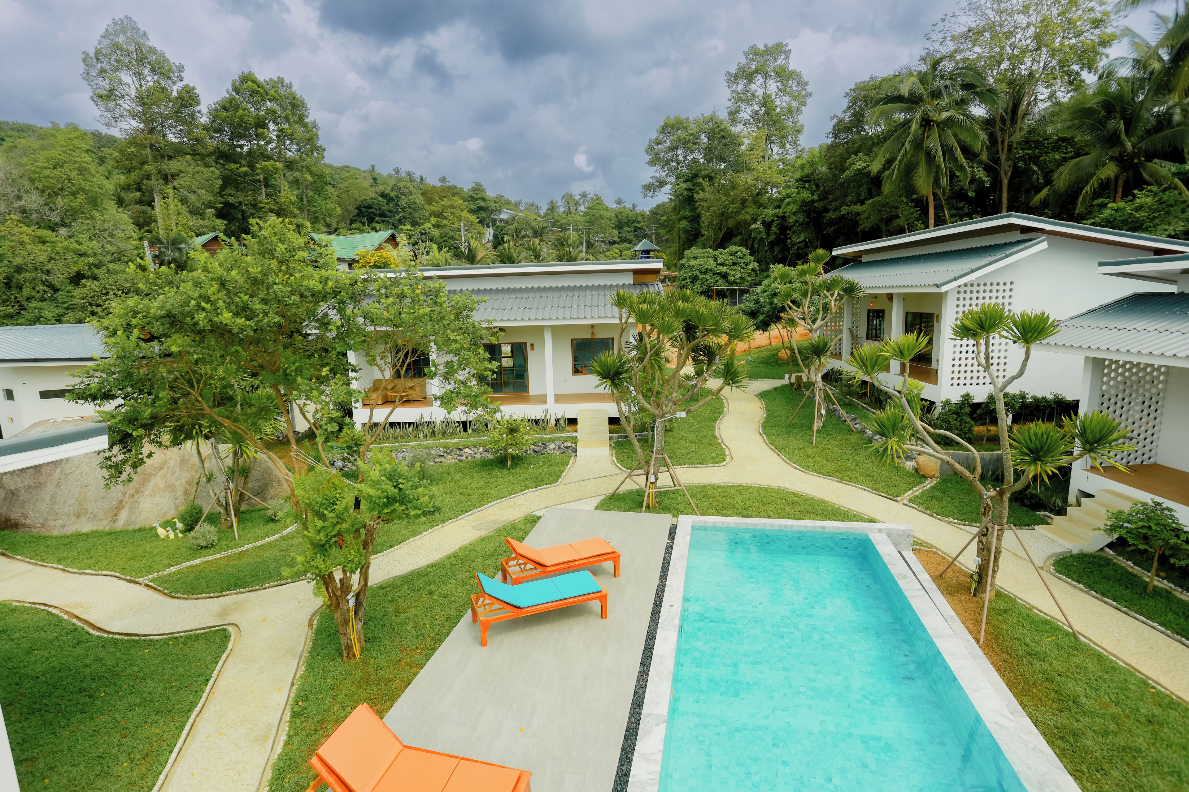 Um resort com piscina, espreguiçadeiras e um jardim exuberante.