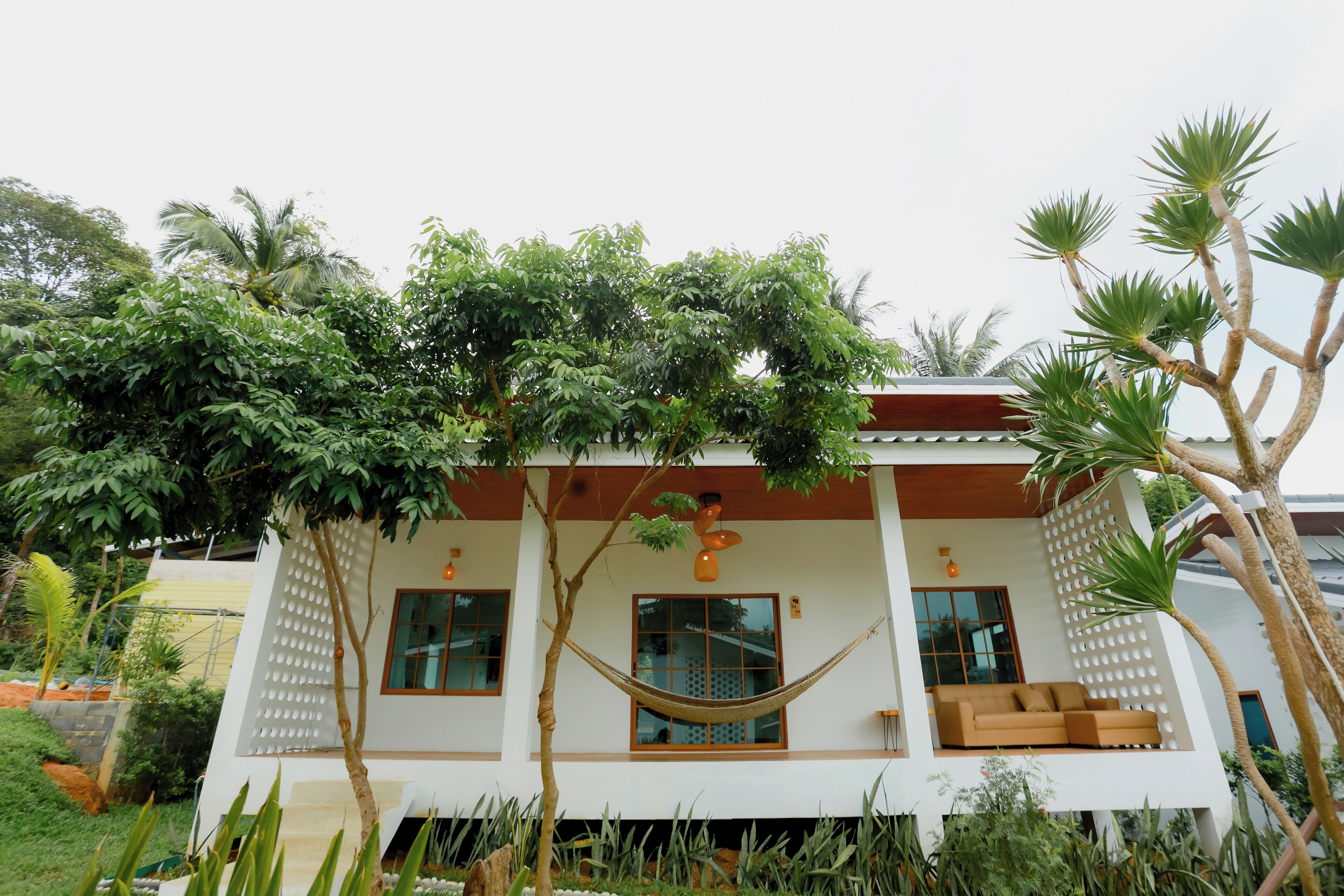 A modern house with a hammock, a balcony, and a garden.