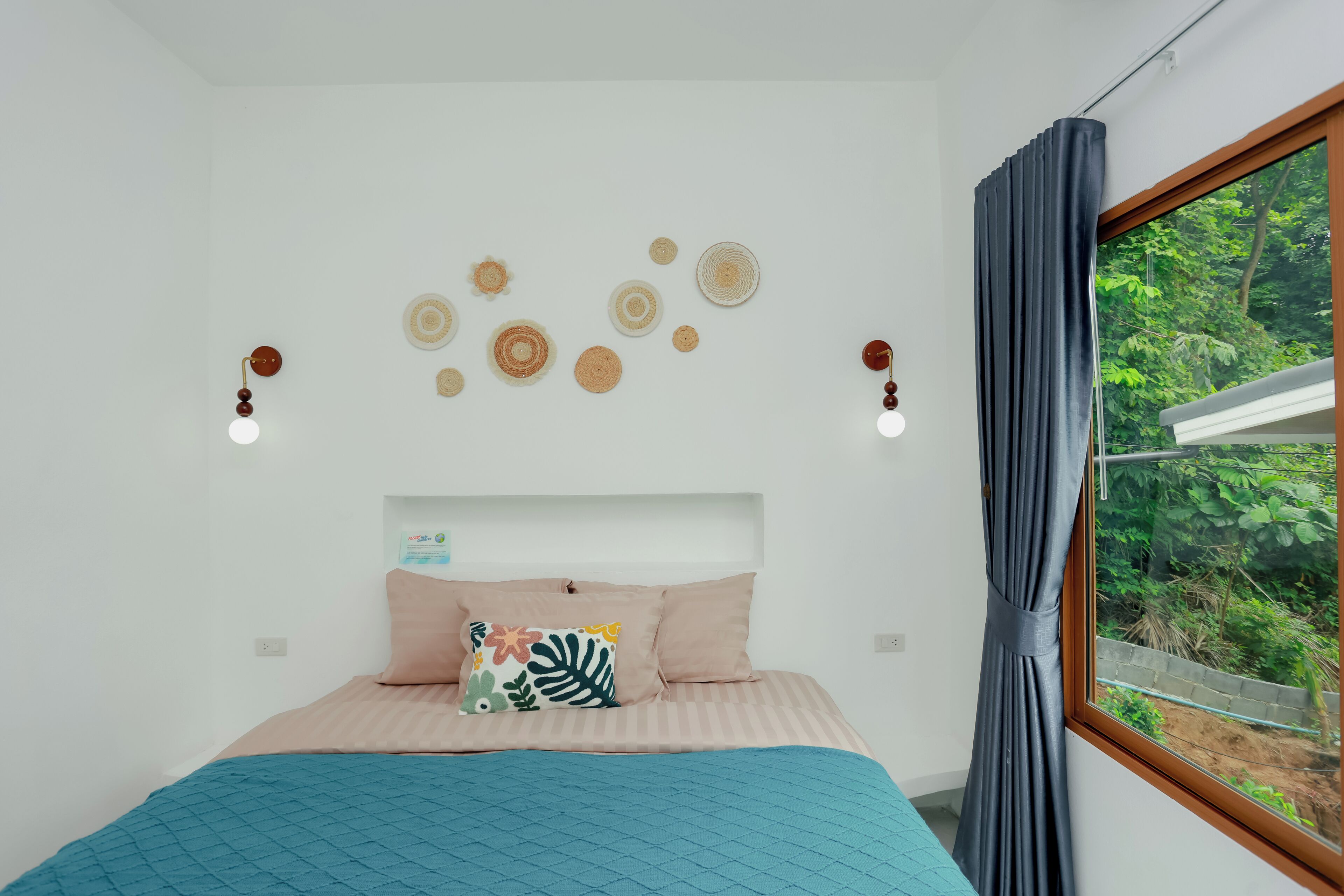 Un dormitorio con cama, ventana con cortinas y adornos en la pared.