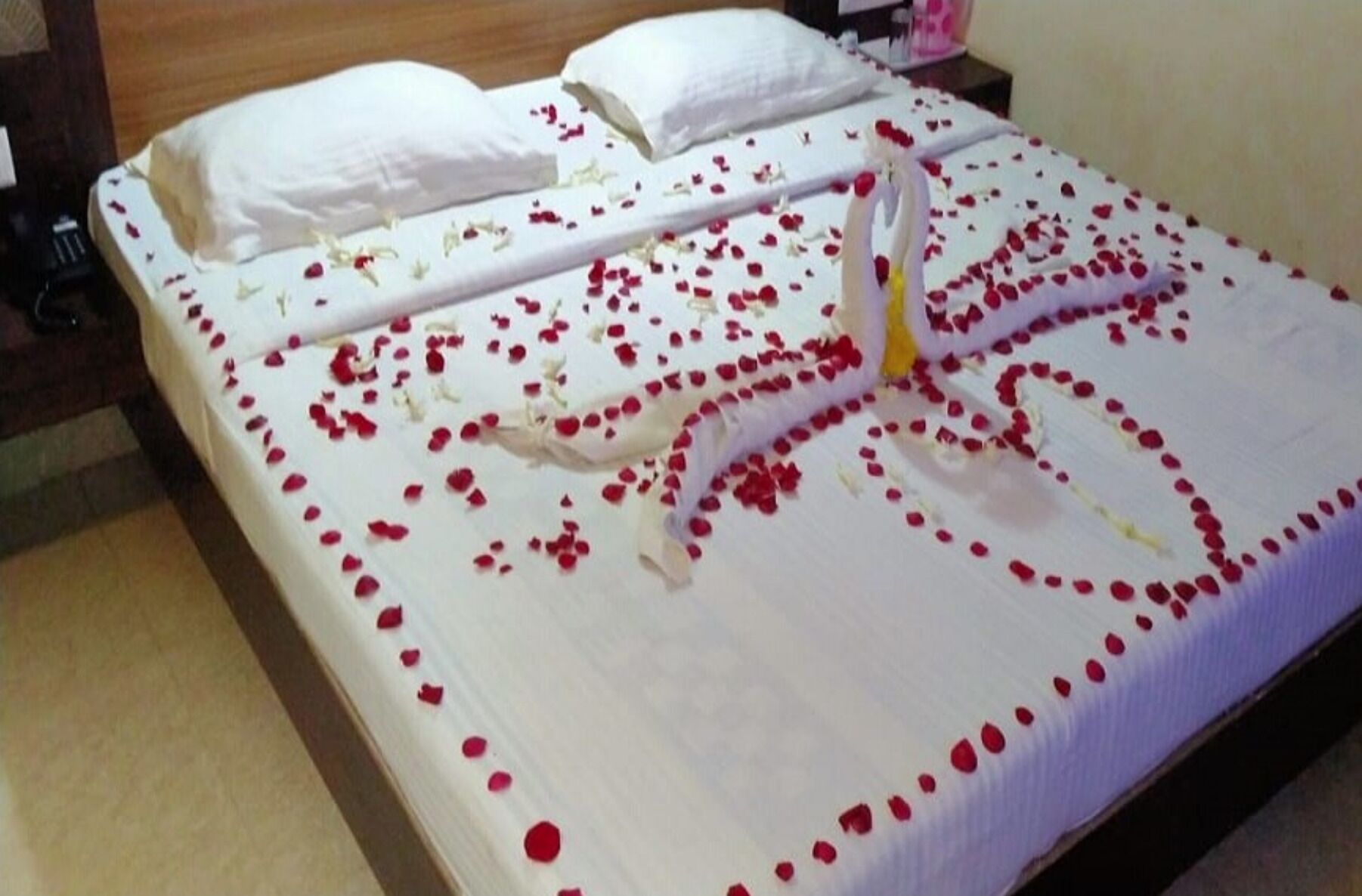A bed with rose petals and a heart-shaped decoration.