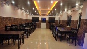 A spacious dining area with marble walls and ceiling, equipped with ceiling fans and recessed lighting. - PP Palace (Puri)