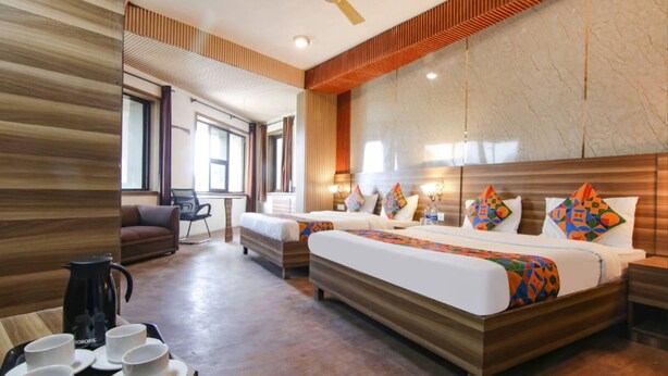 Een hotelkamer met twee bedden, een bureau, een stoel, een koffiehoek en een groot raam.