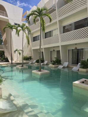 A pool area with clear water, palm trees, and lounge chairs. - Peaceful Jungle Studio in Reverence, Tulum   (Tulum)