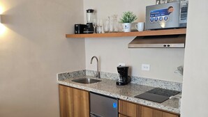 Uma cozinha moderna com geladeira de aço inoxidável, pia e bancada com cafeteira.