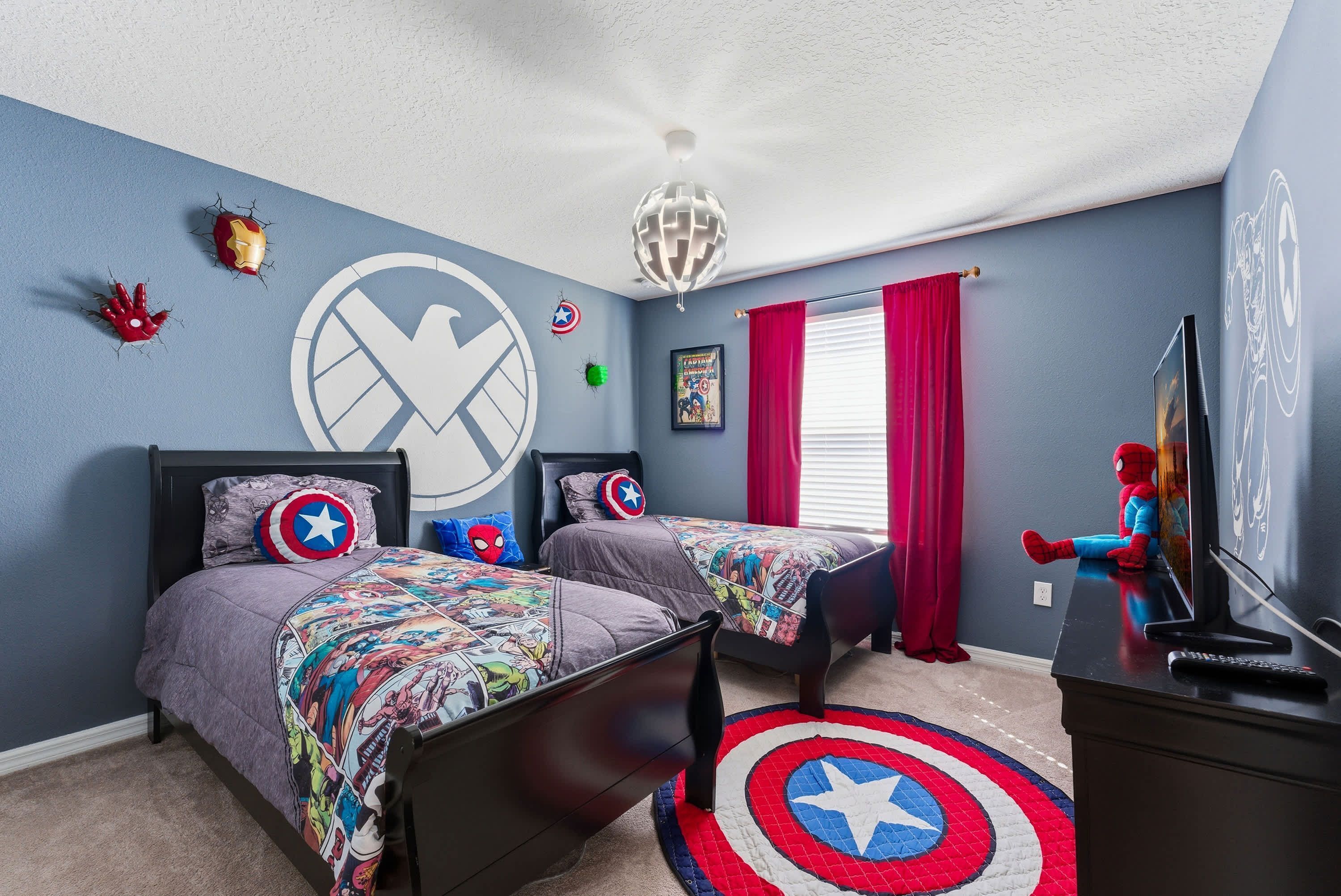 A bedroom with two beds, a Spider-Man figure, and a Captain America pillow.