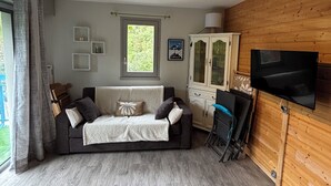 Un salon chaleureux avec un canapé foncé, un meuble blanc et un téléviseur à écran plat fixé à un mur en bois.