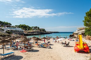 A beach with sun loungers, umbrellas, and a lifeguard stand.