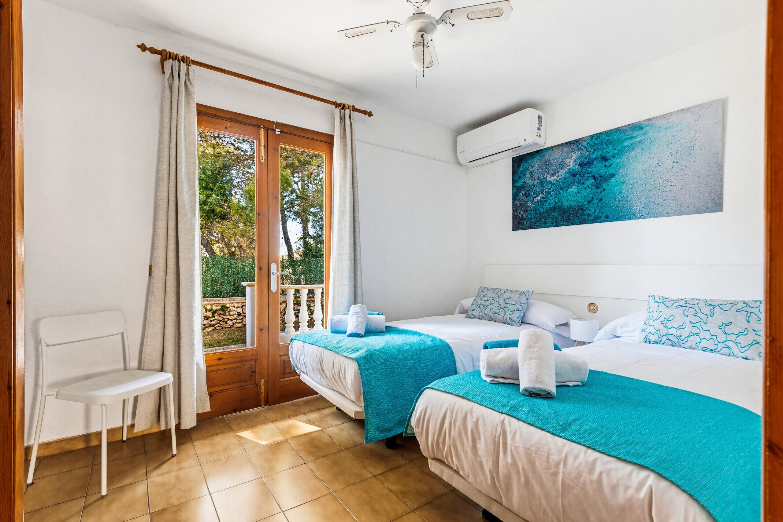 Quarto com duas camas, uma cadeira, porta de varanda e ar condicionado.