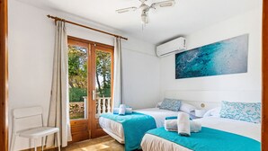 A room with two beds, a chair, a balcony door, and an air conditioning unit.