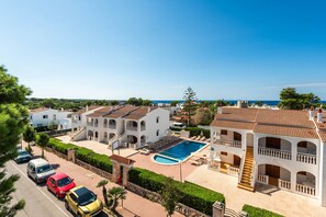 A residential area with a swimming pool, multiple buildings, and parked cars.