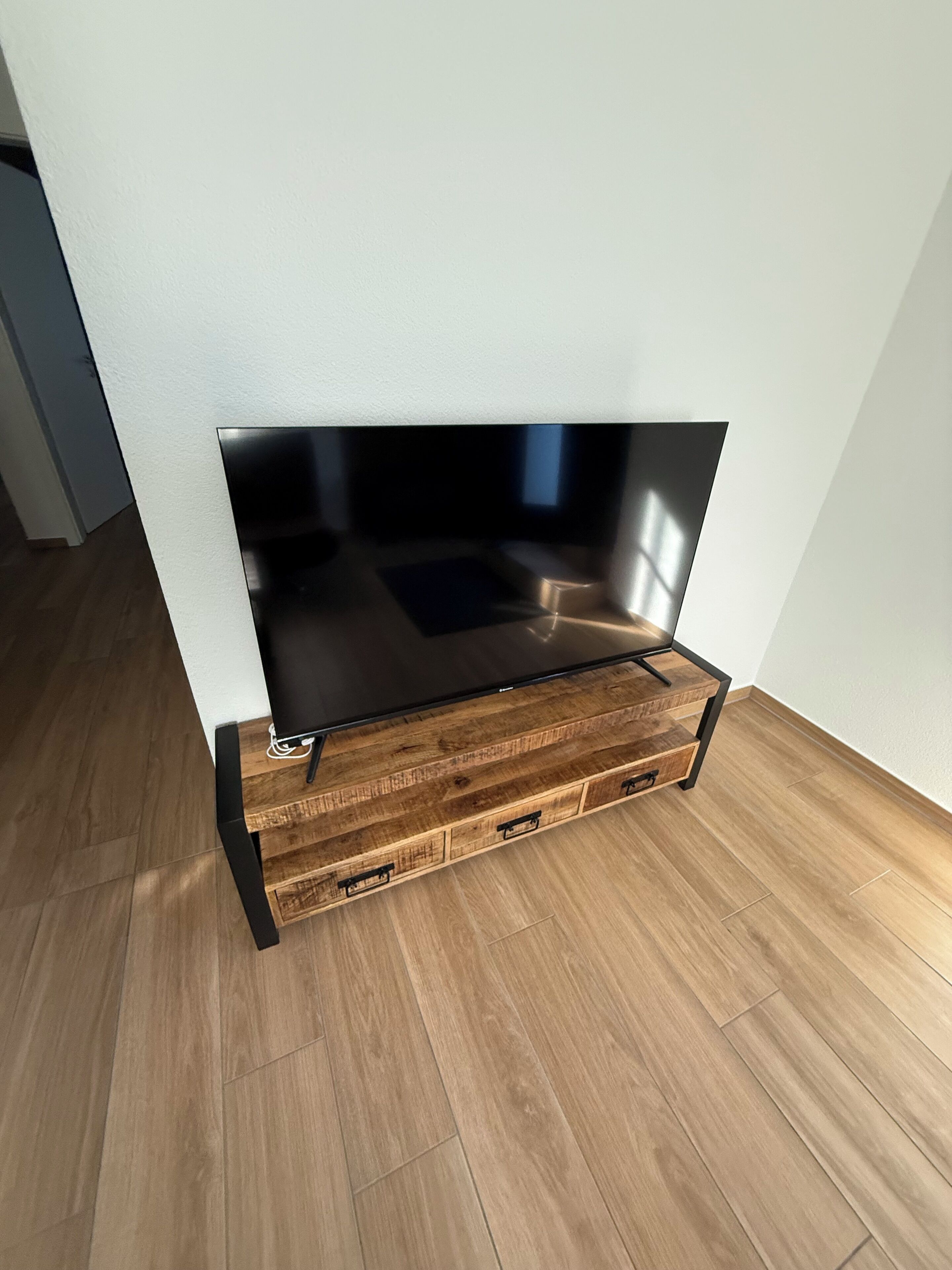 Un televisor de pantalla plana montado sobre un mueble de televisión de madera con cajones.