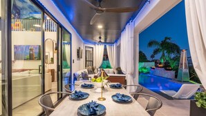 A dining area with a table set for four, a ceiling fan, and a view of a pool and palm trees. - Waterfront,FREE Heated Pool, Spa & therapy Jets! Boat &Kayak! Indoor slides! (Chandler)