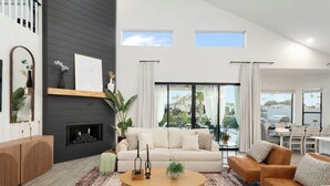 A modern living room with a fireplace, a sofa, a coffee table, and a view of the outdoors. - Waterfront,FREE Heated Pool, Spa & therapy Jets! Boat &Kayak! Indoor slides! (Chandler)