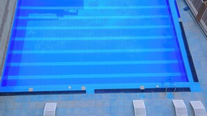 Une grande piscine intérieure dotée de plusieurs couloirs de nage, d’un sol carrelé et de plusieurs chaises longues disposées le long du bord.