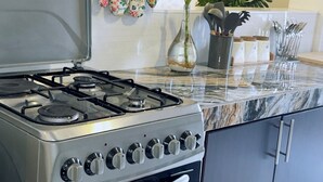 Une cuisine équipée d’une cuisinière à gaz, d’un four et d’un plan de travail en marbre.
