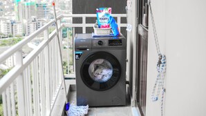Un lave-linge compact et moderne, installé sur un balcon avec vue sur la ville.
