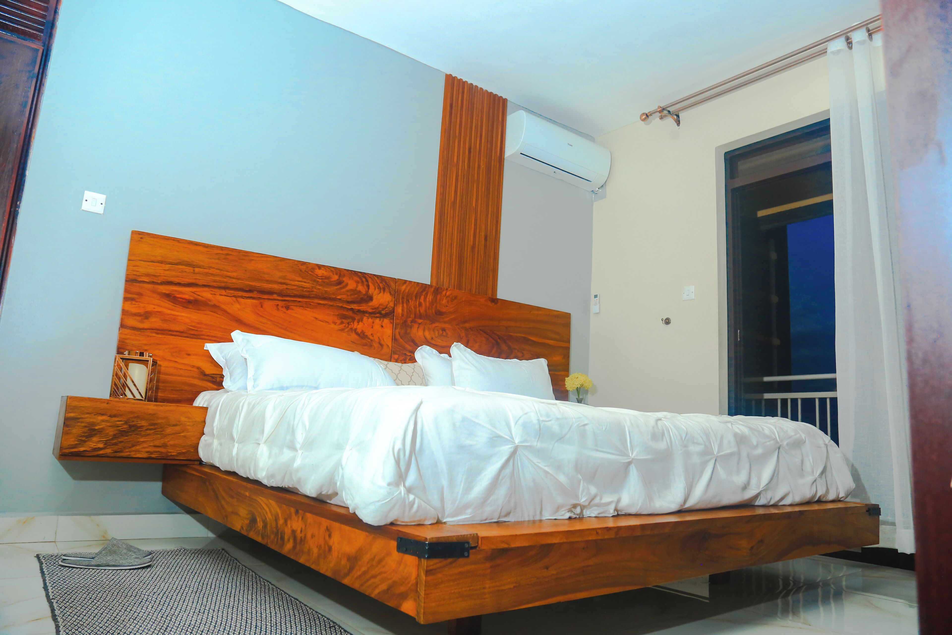 Un letto con una testiera in legno, biancheria da letto bianca e un comodino con una lampada.