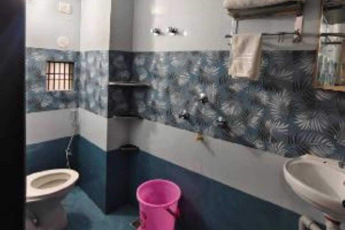 A bathroom with a toilet, sink, and a pink bucket.