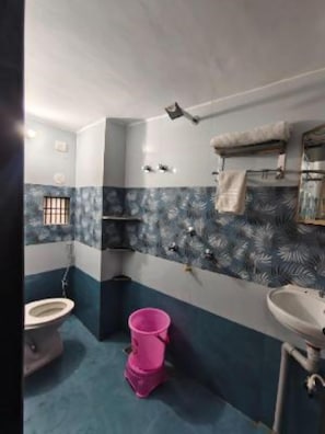A bathroom with a toilet, sink, and a pink bucket. - Nidhipataye Homestay (Varansi)
