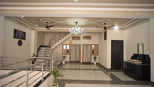 A spacious lobby with a marble floor, a staircase, a chandelier, and a reception desk. - Nidhipataye Homestay (Varansi)