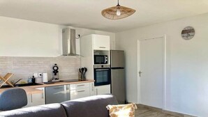 A compact living space with a kitchenette, a sofa, and a dining area. - Ti Zeinga the (Sainte-Anne)