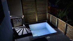 A rooftop pool area with a wooden fence, a metal staircase, and a view of the surrounding vegetation. - Ti Zeinga the (Sainte-Anne)