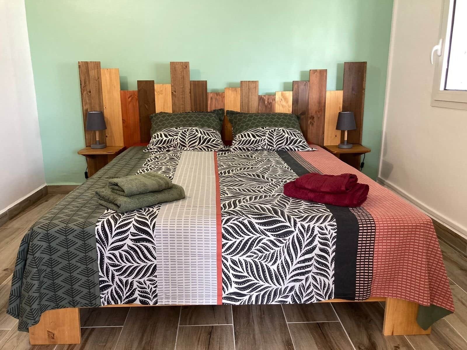 Una cama con ropa de cama estampada, dos mesitas de noche con lámparas y un cabecero de madera.
