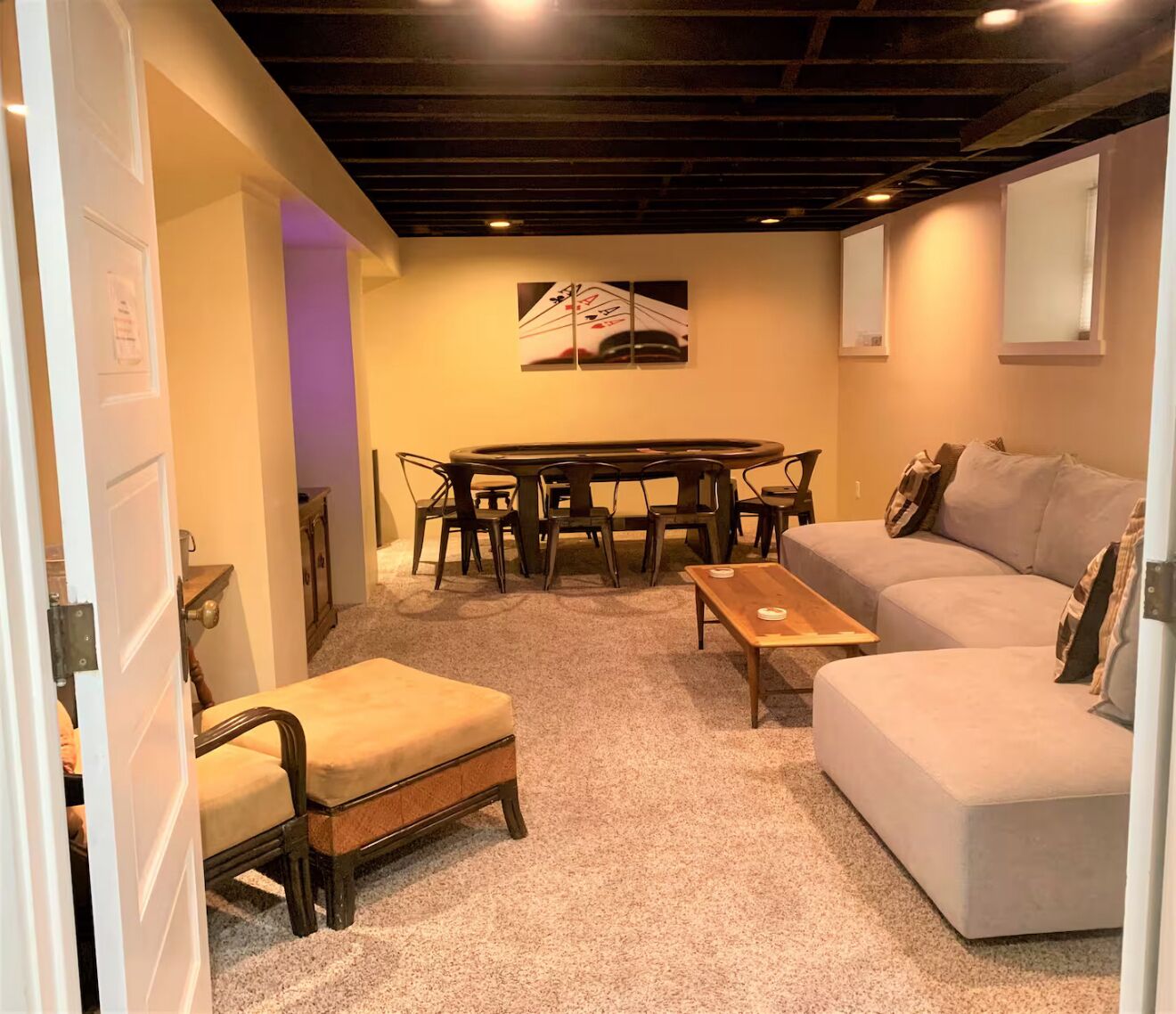 A cozy room with a round table, a sofa, and a chair.