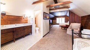 A bedroom with a large window, wooden beams, a bed, a chair, and a small table. - Ultimate Getaway: Expansive Home with Hot Tub & Relaxation (Louisville)
