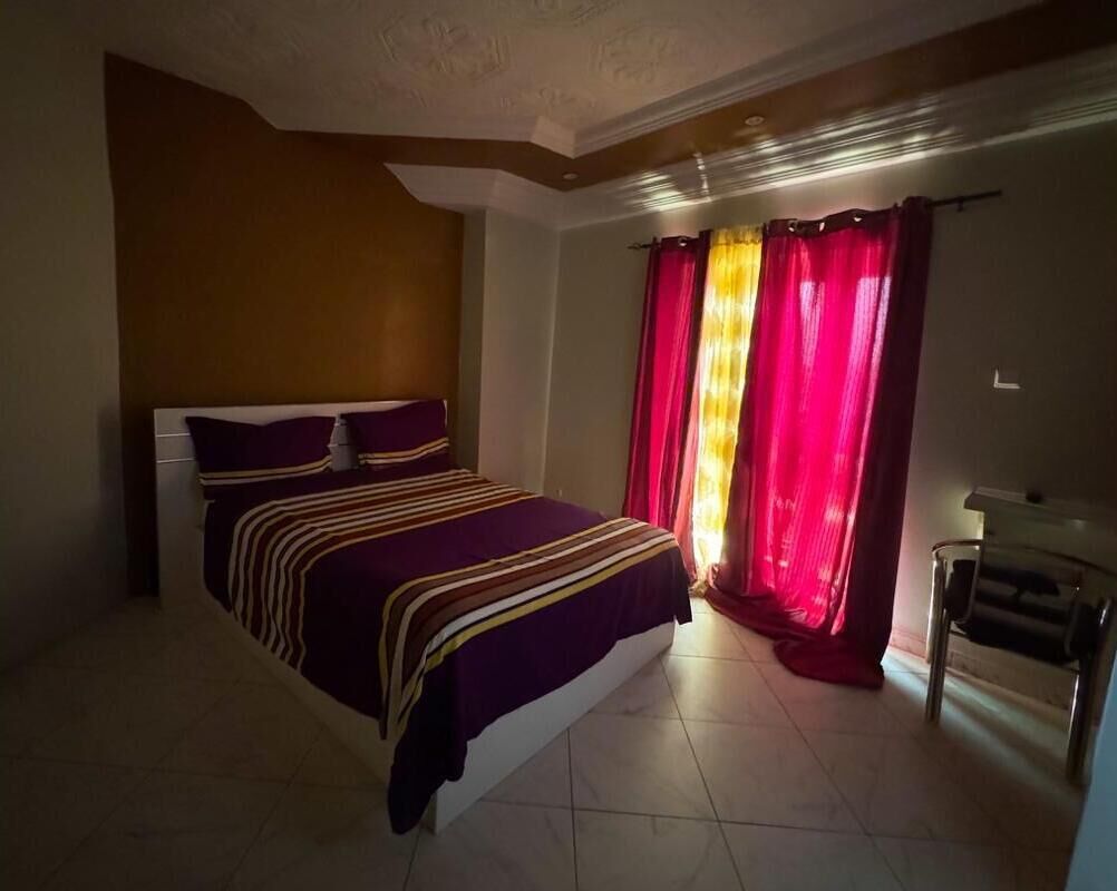 Un dormitorio con cama, cortinas y una silla.
