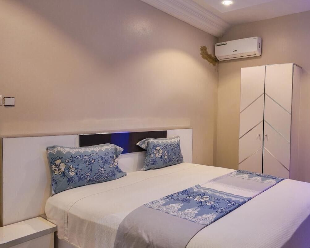 Un dormitorio con cama, mesitas de noche, armario y aire acondicionado.