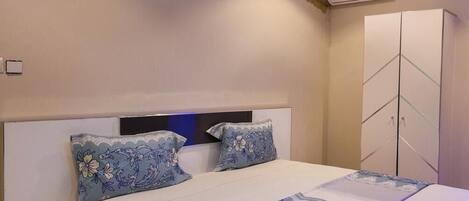 A bedroom with a bed, nightstands, a wardrobe, and an air conditioning unit.
