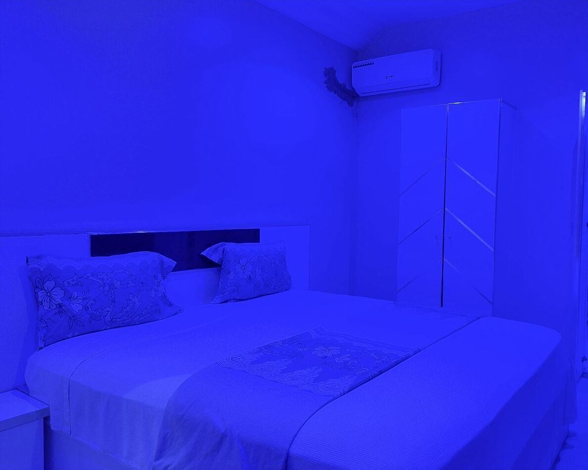 Un dormitorio con cama, mesita de noche, armario y aire acondicionado.