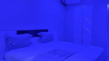 Un dormitorio con cama, mesita de noche, armario y aire acondicionado.